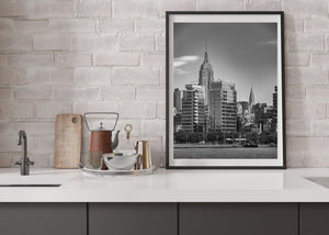 A vertical black and white photograph of Manhattan’s skyline from across the water.