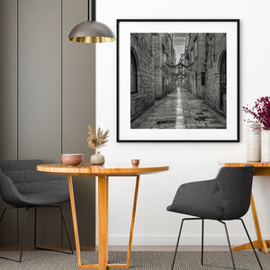 Modern dining room with wooden table, gray chairs, and framed artwork on the wall.