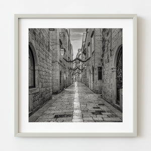 Framed black and white photo of a narrow stone alleyway.