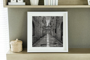 Framed black and white photo of a narrow alleyway on a shelf.