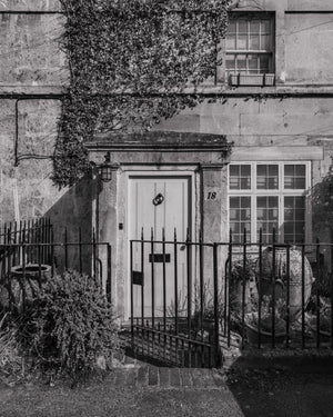 Black and white photograph of an old English doorway and iron railings.