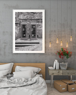 Paired phone booths and textured stone architecture in monochrome.