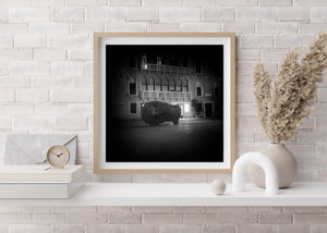 Black and white view of the monumental Eros Bendato head sculpture at night.