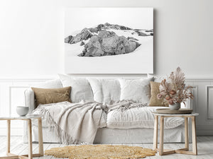 Antarctic rock outcrops create dark shapes across a quiet snowy landscape.