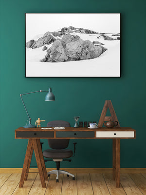 Rugged exposed rock stands against pale snow in an Antarctic landscape photograph.