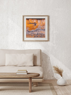 Colour photograph of an exposed pipe on a peeling orange wall in Europe.