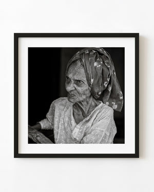 Black and white portrait of an Indian woman wearing a patterned headscarf.