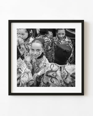 Black and white photograph of a face-painted girl among children at a Tuscan festival.