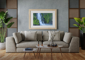 Fine streams trace a green rock face beside a broad Fiordland waterfall.