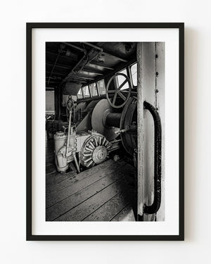 Black and white doorway view of metal machinery and wooden floorboards aboard the Cape Sable fishing trawler.