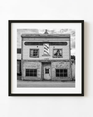 The weathered Flora Dora Hotel in Dawson City, Yukon, with peeling siding and a faded sign in black and white.