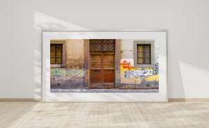 Barred windows flank an aged double door beneath a diamond-patterned grille.