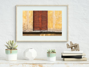 Colour photograph of Florence shutters showing aged wood, horizontal slats and warm wall tones.