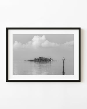 A palm-covered Florida Gulf Coast island and channel marker 18 reflected in calm water in black and white.