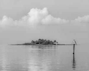 Monochrome seascape of a low tropical island beneath pale clouds on the Florida Gulf Coast.