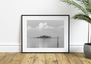 Soft clouds rise above a small Florida island in a quiet black and white photograph.