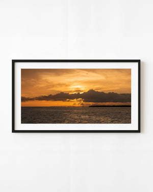 Golden sunset clouds glow above the Seven Mile Bridge and dark water in the Florida Keys.