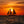 Sailing vessel crossing ocean during orange sunset