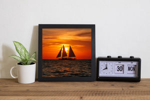 Ocean sunset with sailboat and passengers in silhouette