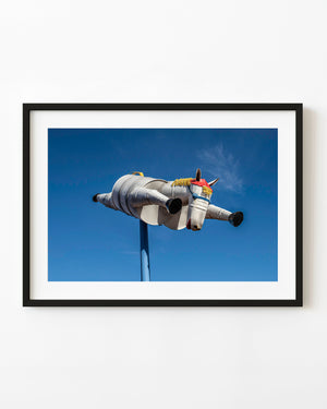 A silver tin horse sculpture stretches its legs in flight against a vivid blue Western Australian sky.