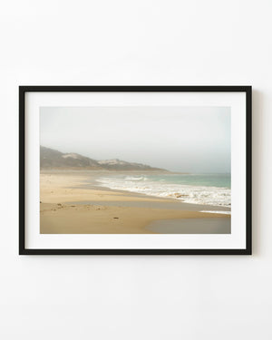 Soft surf washes across golden sand beneath misty dunes on an Australian beach.