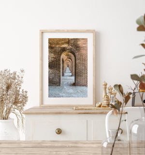 Successive rounded arches frame a narrow passage and pale worn floor.