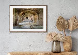 Successive masonry arches lead toward a dark doorway inside Fort Jefferson.