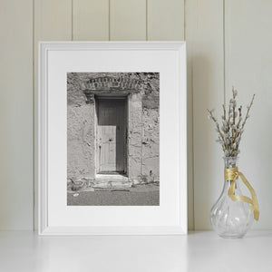 A narrow wooden door with metal fittings is surrounded by worn limestone prison walls