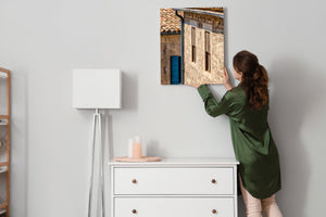 Tall wooden windows and a blue shutter create colour accents on an old stone façade