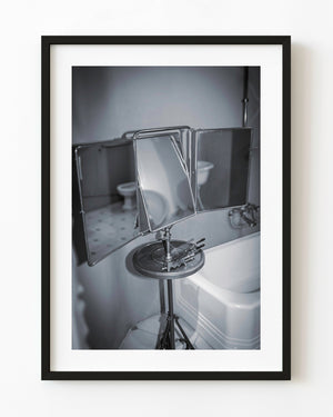 A vintage folding bathroom mirror beside a white bathtub in a Gaudí building, photographed in black and white