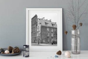 Stepped brick details contrast with a plain plaster façade and tiled roof in a Polish street scene