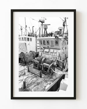 Winches, ropes and a weathered wheelhouse fill a fishing boat deck in Gdańsk in black and white