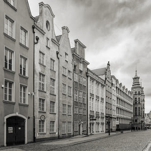 Square monochrome photograph of tall façades and an ornate tower along a Gdańsk street