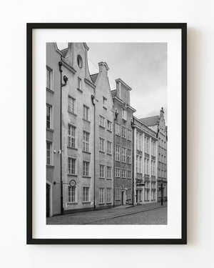Tall gabled façades overlook an empty cobblestone street in Gdańsk in black and white