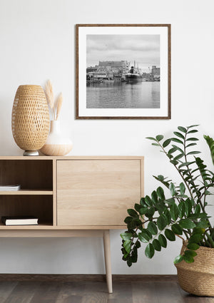 A historic harbor ship and gabled buildings form a monochrome waterfront scene in Gdańsk