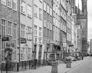 Black and white Gdańsk street scene with tall windows, carved stone railings and shop signs