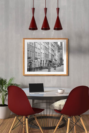 Historic brick and plaster façades recede toward a tall tower along a cobblestone street