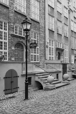 Vertical monochrome photograph of Gdańsk’s library with tall windows and cobblestone pavement