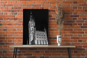 Black and white architectural photograph of Gdańsk’s clock tower beneath a dark night sky
