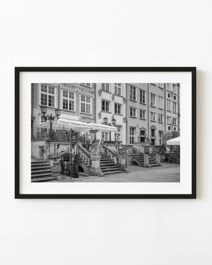 Ornate stone steps and souvenir storefronts line Mariacka Street in Gdańsk in black and white