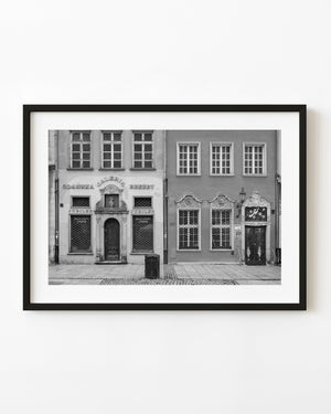 Ornate doors and barred windows line historic Gdańsk storefronts in a black and white photograph