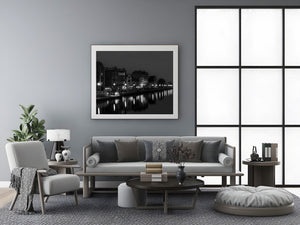 A monochrome Gdańsk riverfront scene with glowing lamps and still water