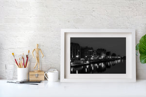 Bright waterfront lights contrast with dark façades and an overcast night sky in Gdańsk