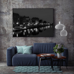 Illuminated windows and riverside lamps cast reflections below old Gdańsk buildings