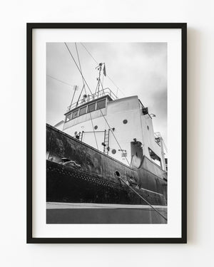 A riveted ship hull and white bridge rise beneath rigging in a black and white Gdańsk photograph