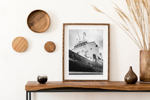 Rigging stretches above rectangular bridge windows and circular portholes on a docked ship