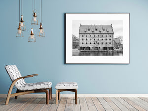 Calm water reflects the base of a historic brick hotel in Gdańsk