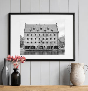 Dark shutters frame arched entrances along a brick building beside Gdańsk’s waterway
