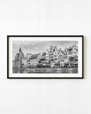 Gabled buildings line the Gdańsk waterfront in a panoramic black and white photograph