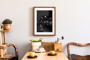 Monochrome night photograph of Gdańsk with glowing restaurant windows and riverside lamps